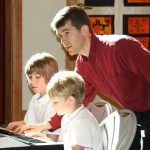 Mike Sakash teaches two young students on the keyboard