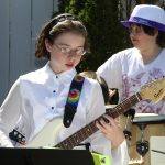 Students performing outdoors on guitar and drums