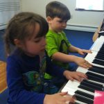 Two preschoolers play piano together