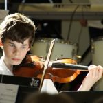 A young boy plays violin