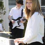 Two youth students perform outdoors on guitar and keyboard